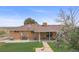 Backyard showing brick home with a covered patio and well-maintained lawn at 12101 Riverdale Rd, Brighton, CO 80602