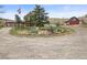 Rural property featuring a house, red barn, and a unique decorative island in the circular driveway at 12101 Riverdale Rd, Brighton, CO 80602