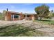View of the house with a brick foundation, a gravel front yard, and a well-maintained lawn at 12101 Riverdale Rd, Brighton, CO 80602