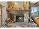Close up of the stone fireplace with a rustic wooden mantel and a cozy fire burning at 12101 Riverdale Rd, Brighton, CO 80602