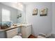 Well-lit half bathroom featuring a mirrored vanity, floral wall art, and hardwood floors at 60 S Moline St, Aurora, CO 80012
