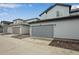 A view of multiple two-car garages with gray siding and paved driveways at 1418 Hudson Pl, Longmont, CO 80501