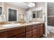 Bathroom featuring double sinks, brown vanity and a decorative mirror at 6303 Ellingwood Point Pl, Castle Rock, CO 80108