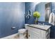 Stylish powder room features blue walls, a modern sink with chrome fixtures, and a decorative peace sign at 6303 Ellingwood Point Pl, Castle Rock, CO 80108