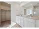 Bathroom featuring double vanity with white cabinets, large mirror, and walk-in closet at 19019 E 94Th Pl, Commerce City, CO 80022