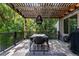 Inviting deck with modern outdoor dining set and a pergola, surrounded by mature trees at 14152 W Evans Cir, Lakewood, CO 80228