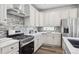 Bright kitchen features white cabinets, stainless steel appliances, and stylish backsplash at 5142 N Quemoy Ct, Aurora, CO 80019