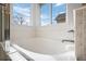 A relaxing soaking tub area offers natural light from a large window and features white tile at 15028 Clayton St, Thornton, CO 80602