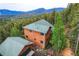 Stunning aerial view of the wood-sided home nestled among lush trees with mountain backdrops at 11876 Coal Creek Heights Dr, Golden, CO 80403
