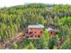 Aerial view showcases beautiful house surrounded by towering trees, deck, and lush landscaping at 11876 Coal Creek Heights Dr, Golden, CO 80403
