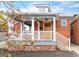 Charming brick home featuring a covered front porch, white columns, and manicured landscaping at 120 Cherokee St, Denver, CO 80223