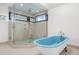 Bright bathroom featuring a glass shower with seating and a freestanding blue bathtub with modern fixtures at 375 S University Blvd, Denver, CO 80209