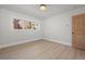 A brightly-lit bedroom featuring light wood floors and trim, with a large window and wooden door at 375 S University Blvd, Denver, CO 80209