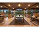 Elegant covered patio with wood ceiling, stone accents, dining area, and outdoor kitchen at 6111 Huron Pl, Castle Rock, CO 80108