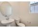 Neat half bathroom with pedestal sink, modern toilet, and a window providing natural light at 11039 Snowdon St, Parker, CO 80134