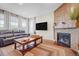 Inviting living room featuring a brick fireplace, hardwood floors, and large windows for natural light offers warmth at 16043 Azalea Ave, Parker, CO 80134