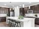 Modern kitchen with dark cabinets, subway tile backsplash, stainless steel appliances, and an island with stool seating at 8814 S Winnipeg Ct, Aurora, CO 80016