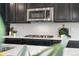 Close-up of modern gas range stove with a white backsplash and counter, stainless microwave, and dark wood cabinets at 8814 S Winnipeg Ct, Aurora, CO 80016