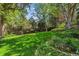 Serene backyard with a large grassy area, mature trees, and garden beds, creating a peaceful outdoor oasis at 9113 E Evans Way, Denver, CO 80231