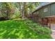 Beautifully landscaped backyard with vibrant greenery, flower beds, and a multi-level deck for outdoor enjoyment at 9113 E Evans Way, Denver, CO 80231