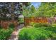 Landscaped backyard featuring a stone pathway, lush greenery, and a charming wooden fence, offering privacy at 9113 E Evans Way, Denver, CO 80231