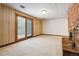 Spacious basement area with a brick fireplace, sliding glass doors, and neutral carpeting at 9113 E Evans Way, Denver, CO 80231