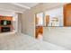 Open living room with brick fireplace, neutral carpet, and easy access to the kitchen at 9113 E Evans Way, Denver, CO 80231