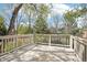 A sun-drenched wooden back deck with white railings, surrounded by mature trees and blue skies at 13071 Emerson St, Thornton, CO 80241