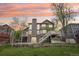 Exterior home elevation featuring two-tiered decks, mature landscaping, and a stone retaining wall at 13071 Emerson St, Thornton, CO 80241