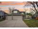 Charming two-story home with a three-car garage and beautifully landscaped front yard against a colorful sunset sky at 13071 Emerson St, Thornton, CO 80241