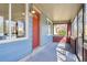 Inviting enclosed front porch with windows, a red door, and bright blue siding at 3527 W 44Th Ave, Denver, CO 80211