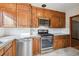 Galley kitchen featuring wood cabinetry, stainless steel appliances, and white backsplash at 2630 Albion St, Denver, CO 80207