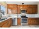 Galley kitchen featuring wood cabinetry, stainless steel appliances, and a window above the sink at 2630 Albion St, Denver, CO 80207