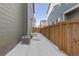 Side view of a fenced backyard with a patio showing the home's siding and utility connections on a snowy day at 28334 E 6Th Pl, Aurora, CO 80137