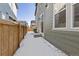 Side view of a quaint fenced backyard with a small patio and sliding door access on a snowy day at 28334 E 6Th Pl, Aurora, CO 80137