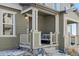 Inviting covered front porch with a cozy seating area, decorative pillows, and stylish outdoor lighting fixture at 28334 E 6Th Pl, Aurora, CO 80137