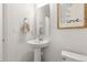 Clean and modern half-bathroom with a pedestal sink, framed mirror, and stylish decor at 28334 E 6Th Pl, Watkins, CO 80137