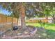 Picturesque backyard with mature trees, brick lined bed, and a wooden fence at 6436 Otis St, Arvada, CO 80003