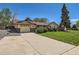 Ranch-style home with a large concrete driveway, garage, and well-kept front lawn at 6436 Otis St, Arvada, CO 80003