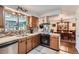 Traditional kitchen with oak cabinets, mosaic backsplash, stainless hood, and view to dining room at 6436 Otis St, Arvada, CO 80003