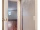 View through an open bathroom door to a bedroom with wood floors and a bright window at 547 S Flower St, Lakewood, CO 80226