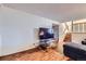Spacious living area with wood floors, large TV, and staircase access, creating a flexible living space at 547 S Flower St, Lakewood, CO 80226
