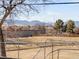 A view of an expansive backyard with mountain views in the distance from behind a chain link fence at 8331 Oakwood St, Westminster, CO 80031