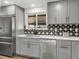 Stylish kitchen featuring stainless steel appliances, gray cabinets, and a decorative tile backsplash at 8331 Oakwood St, Westminster, CO 80031