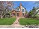 Charming Tudor-style home with brick facade, lush lawn, and blooming tree at 1650 Locust St, Denver, CO 80220