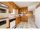 Cozy kitchen with wood cabinets, white appliances and retro flooring leading to dining area at 8895 Morton Rd, Niwot, CO 80503