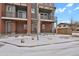 Two-story townhome with brick and gray siding, balconies, and snowy front yard at 7870 W 43Rd Pl, Wheat Ridge, CO 80033