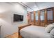 Bedroom with wood floors and an accent wall features a TV and decorative wood panels at 2500 Walnut St # 201, Denver, CO 80205