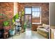 Bright corner of a living space features exposed brick, a comfortable chair, and ample natural light at 2500 Walnut St # 201, Denver, CO 80205