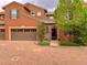Charming stucco townhome featuring a two-car garage, stone accents, and lush landscaping at 9238 Viaggio Way, Highlands Ranch, CO 80126